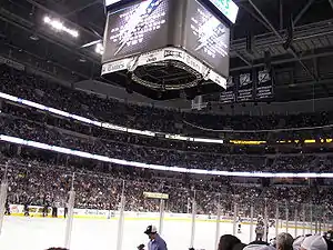 An indoor arena with a roof which has three levels full of fans surrounding an ice rink