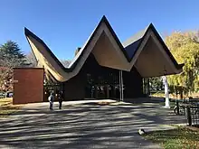 a single level church with a crazy swooping triangle roofline sits amongst trees