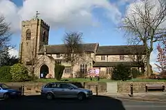 A complex stone church seen from the south with a porch, transept, separate clerestories over the chancel and nave, and a west tower.