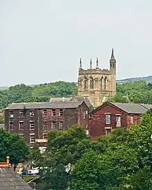 A Gothic tower projecting above rooftops, with a taller spired stair turret