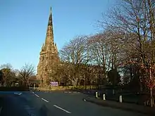 A church with an embattles body, and a west tower with pierced pinnacles and a recessed spire