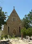 Rectangular stone building with steep slate roof and a straight-sided gable at its front end.
The choir behind, following the same form, is an 1876 addition.
The building known as "St John the Evangelist" is probably the most unaltered example of the work of Sophia Gray, the wife of Bishop Robert Gray, first Anglican Bishop of Cape Town.
Since the arrival of the Grays in the Cape in 1843, Sophia Grey was respo
Type of site: Church
Current use: Church : Anglican.
This neo-Gothic church building, designed by Sophia Gray, was erected in 1865 on the remains of an earlier Settler church.
The building was inaugurated in 1866 by Bishop Gray.
The parsonage, which presumably dates from the 1840s, is an exceedingly beautiful