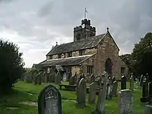 A stone church seen from the southeast with at the northwest a tower and a taller stair turret.