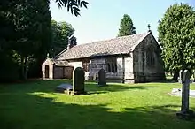 A low small stone church with a south porch and west bellcote.