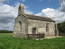 A small chapel seen from the south, with a bellcote at the left, a door and a single window