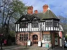 A two-storey building seem from a small angle, the lower storey in stone, the upper timber-framed; at the top are two small gables and on the corner is a small turret.