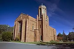 Image of side of church, brick construction with bell tower in foreground