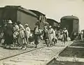 Passengers, leaving the New South Wales Railways carriage on the right side, transferring to a Queensland train on the left at Clapham Junction, Moorooka, probably during WW2