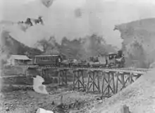 Steam tram crossing Irvinebank bridge over Gibbs Creek ~1911. Locomotive is called Baby and is on a picnic tour to Stannary Hills. (Description supplied with photograph).