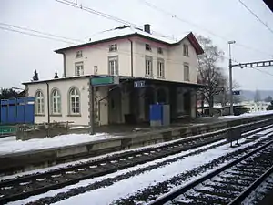 Two-story building with gabled roof next on side platform