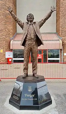 statue of man in suit with arms aloft in triumph