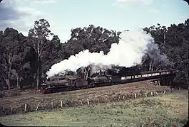 Photo of steam engines hauling a special passenger train over the Blackwood River bridge and past farms close to Nannup