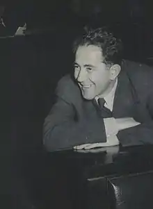 Man wearing a dark suit, smiling and leaning forward