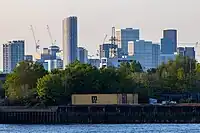 The emerging cluster in Stratford in April 2023 as viewed from Greenwich Peninsula. Stratford has been undergoing regeneration, associated with the 2012 Summer Olympics, which largely took place in Queen Elizabeth Olympic Park to the west of the cluster. Seen on the left is 150 High Street at a height of 135m. The tallest building in the cluster, Manhattan Loft Gardens at 143m, is seen at the back.