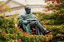 A statue of Donald Stuart surrounded by trees leaves and branches