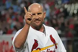 A man in a white baseball jersey smiling