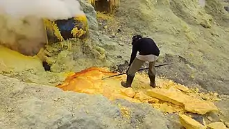 Person stabbing a yellow mineral block