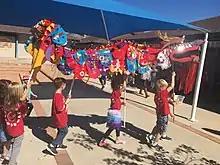 Students holding a dragon decoration at a parade.