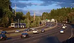 Photograph of a train running next to a busy freeway on the right