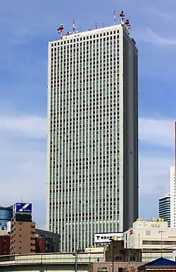 Ground-level view of a gray, rectangular high-rise lined with columns of windows