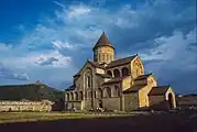 A compact tall stone church with a circular tower above the apsis.