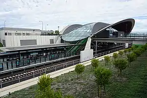 Picture of Tallawong station viewed from the outside. It consists of a curved roof covering a platform in a cutting below ground.