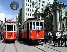 2 old red and white electric trams in a big-city street