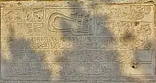 photo of a stone slab with Arabic lettering, and a Sultan's tughra in the upper middle