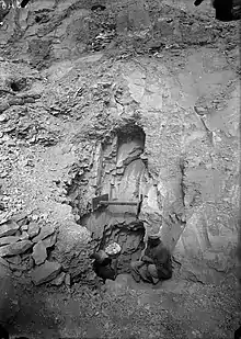 Two men work in and around an irregularly shaped pit