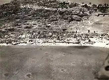 Aerial view of Betio Island, 24 November 1943, looking north toward "The Pocket", the last place of Japanese resistance. An emplacement just onshore with two 12.7 mm anti-aircraft guns is visible near the left edge of the photograph.