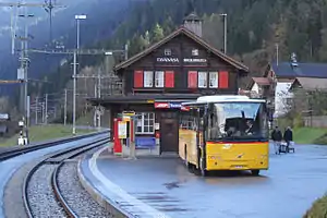 Two-story wooden building with gabled roof next to double-track railway line