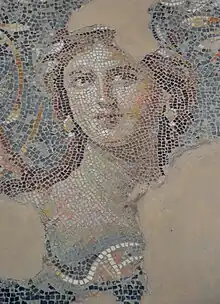 Damaged mosaic depicting the bust of a white woman crowned with laurel.