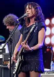 A woman playing a black and white electic guitar