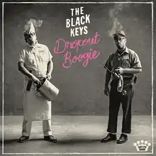 A black-and-white photo of the band dressed as a chef and a janitor. The band's name is colored in white and the album title is written in pink cursive text.