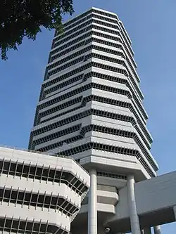 Ground-level view of a building with an octagonal cross-section; the facade is white with dark, receded windows that appear to be continuous ridges from a distance