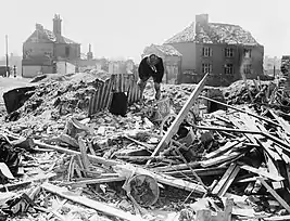 Three Anderson shelters standing intact amid a scene of debris in Norwich