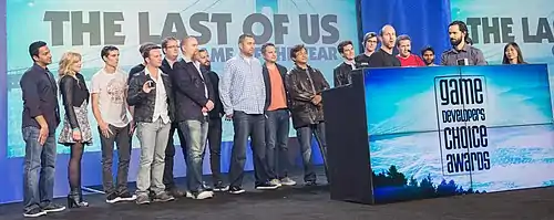 A group of 19 people accepting an award on a stage.