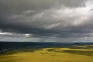 Rolling green tundra hills and a river on the North Slope