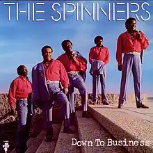 The group standing on stairs in matching red and blue suits