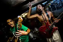 Two men performing while holding Guitars