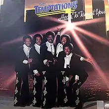 The band in matching suits on a stage, smiling