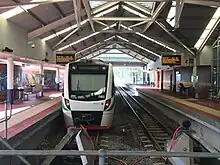 Brick train station with side platforms and a train parked on the left platform