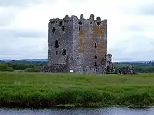 A castle in the centre, grass and water in the foreground, sky and landscape in background