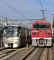 A 12-000 series EMU (left) and a class E5000 electric locomotive (right). The class E5000 locomotive is used to haul 12-000 series units to Magome depot for major overhauls.