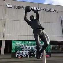 A statue of a goalkeeper in front of a football stadium