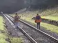 Track workers walking the line through the old station with the tunnel beyond