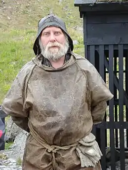 Man wearing sea clothing. The type of shirt pattern he is wearing underneath became popular in the 19th century.