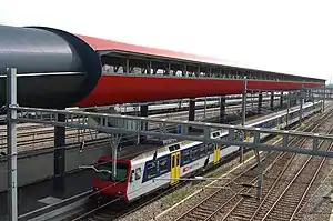 Red-colored enclosed walkway above single side platform