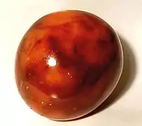 A tumbled carnelian (golden-orange chalcedony, coloured by iron oxide impurities)