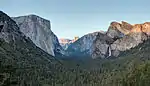 Forested valley lined by large rocks.